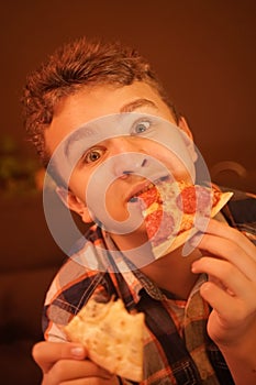 Teen boy eats pizza and enjoys it, closeup enjoying and savoring.