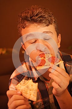 Teen boy eats pizza and enjoys it, closeup enjoying and savoring.