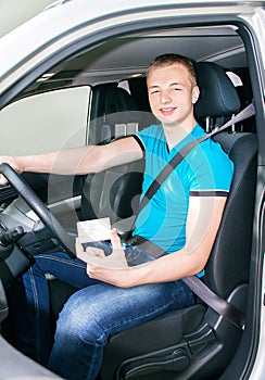 Teen boy fastening seat belt and showing driver license