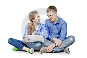 Teen boy and girl sitting with tablets