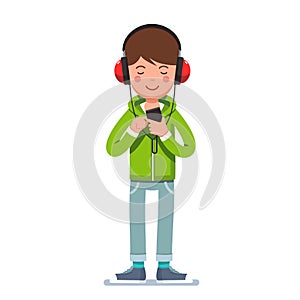 Teen boy in headphones listening to music on phone