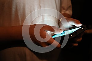 Teen boy holding smart phone in low light