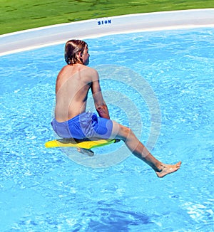 Teen boy jumping in the blue pool