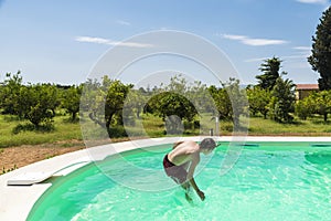 Teen boy jumping in pump in an outdoor pool