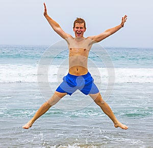 Teen boy jumps up the beach