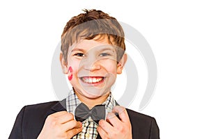 Teen boy with lipstick print on cheek straightens bow tie on white isolated background