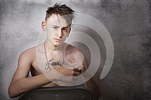 Teen boy looking aggressive and sitting on a chair