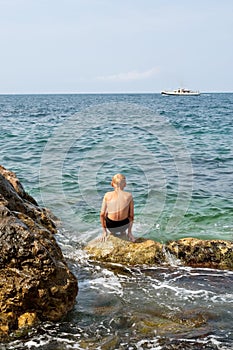 Ragazzo aspetto sul il mare una barca 