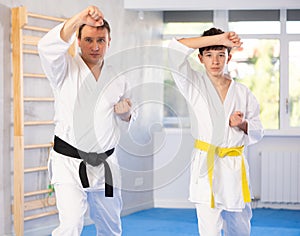 Teen boy and middle-aged man wearing kimono training karate techniques