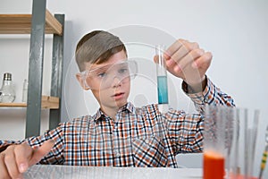 Teen boy is mixing blue color pill in tube doing chemistry experiments.