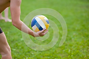 Teen boy playing beach volleyball. Volleyball player on the grass playing with the ball, a volleyball ball in his hand