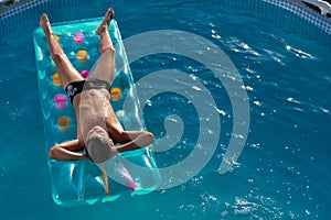 Teen boy in the pool, floats on an inflatable mattress, top view