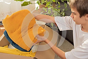 Teen boy preparing itemsfor charity and packing into donation box at home. Donations for charity, help low income