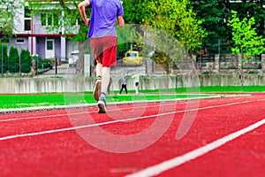 Teen boy running along the stadium track,a soccer field with green grass,concept of sports and healthy life.boy in sportswear