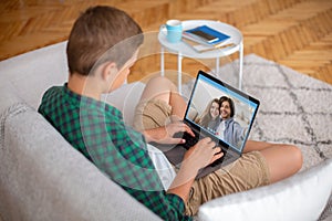 Teen Boy Sitting On Couch With Laptop, Videoconferencing With Family Or Friends