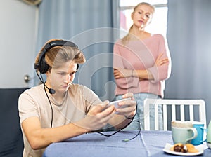 Teen boy with smartphone not paying attention to upset mother