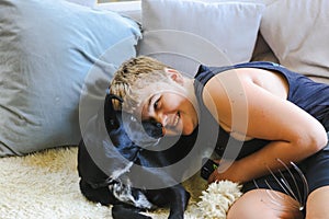 Teen boy snuggling on couch with pet dog. Man's best friend. Black kelpie x labrador breed