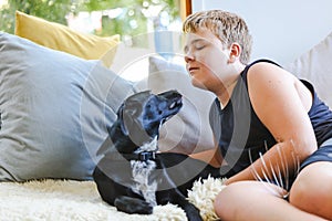 Teen boy snuggling on couch with pet dog. Man's best friend. Black kelpie x labrador breed