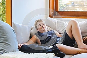 Teen boy snuggling on couch with pet dog. Man's best friend. Black kelpie x labrador breed
