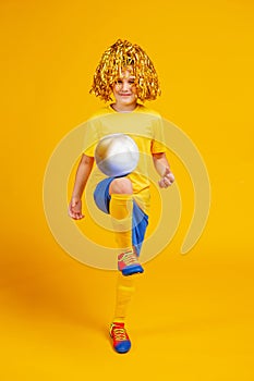 Teen boy with a soccer ball and pompons for fans on his head