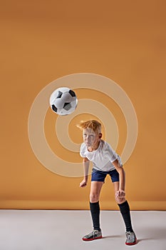 Teen boy soccer player kicking ball with head