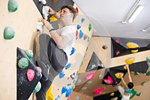 Teen guy practicing rock climbing on climbing wall