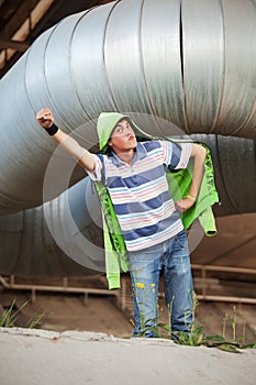 Teen boy superhero under industrial pipeline