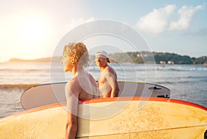 Teen boy with surfboard go to the sea for surfing with father on Sri Lanka island. They have a winter vacation and enjoying a