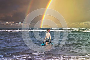 Teen boy in the swim flippers snorkeling mask and tude in the sea wave on the rainbow background