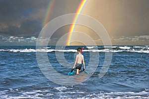 Teen boy in the swim flippers snorkeling mask and tude in the sea wave on the rainbow background