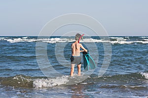 Teen boy in the swim flippers snorkeling mask and tude in the sea wave