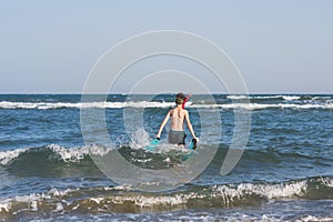 Teen boy in the swim flippers snorkeling mask and tude in the sea wave