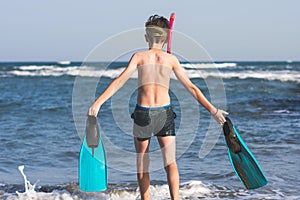 Teen boy in the swim flippers snorkeling mask and tude in the sea wave