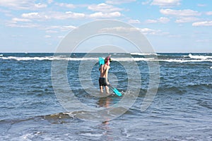 Teen boy in the swim flippers snorkeling mask and tude in the sea wave