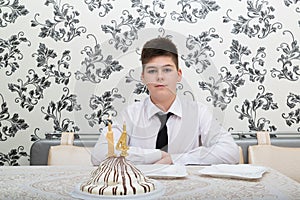 teen boy at table with cake for his fourteenth birthday photo