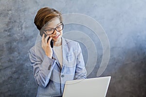 Teen boy talking over mobile phone and using laptop