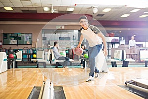 Teen Boy Throwing Ball While Practicing Bowling Game In Club