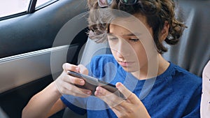 Teen boy uses phone while traveling in car
