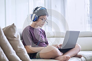 Teen boy using a laptop and headphones at home
