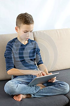 Teen boy using tablet. Child boy playing game or checking social media on tablet during recreation time at home.