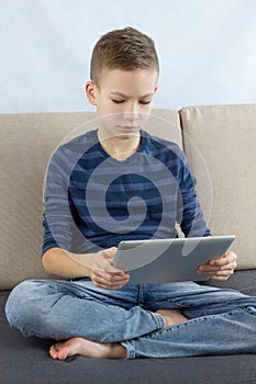 Teen boy using touchscreen tablet. Young boy playing game or checking social media on tablet at home. Internet online education