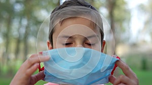 Teen boy wearing medical mask outdoors. Young guy protecting from covid19.