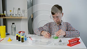 Teen boy is wearing protective glasses and doing chemistry experiments.
