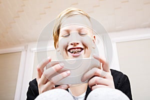 Teen with braces on his teeth with phone