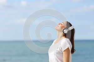 Teen breathing fresh air listening to music on the beach