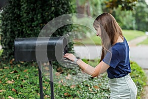A teen brunette girl with long hair checking the mailbox for letters and packages.