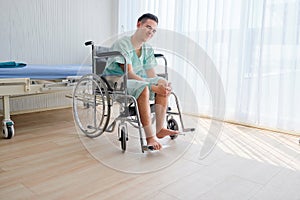 Teen Caucasian male patient having knee pain,sitting on wheelchair in the hospital