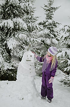 Child, snowman and winter forest