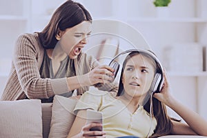 Teen closed ears with headphone while mom yells