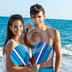 Teen couple with beach tennis rackets.